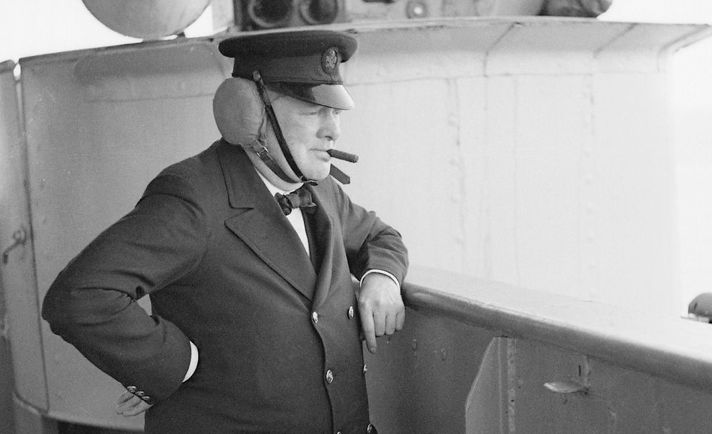 Winston Churchill, with leather ear guards, watching gunnery practice on HMS Renown
