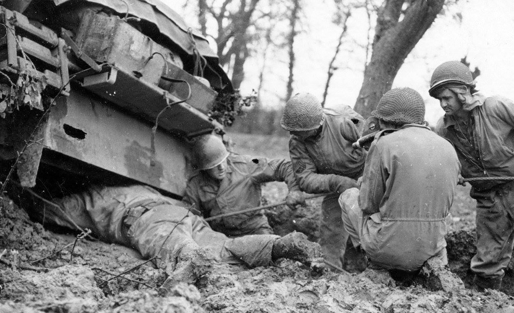 US Crewmen Battling Deep Mud to Find the Towing Shackle on what looks to be an M4A3